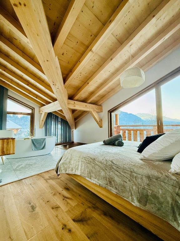 une chambre avec un grand lit et une grande fenêtre dans l'établissement Chalet Monarch - Les Carroz - Sauna, Spa & vue Montagnes, à Arâches-la-Frasse