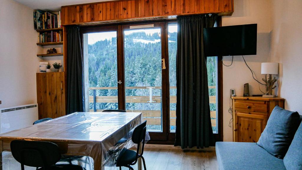 un salon avec une table et une grande fenêtre dans l'établissement Appartement Proche Des Pistes By TerraAlpina, à Saint-Gervais-les-Bains