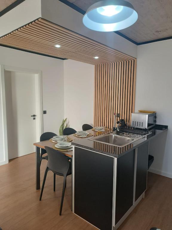 a kitchen with a sink and a table with chairs at Kings B&B Eiras in Caniço