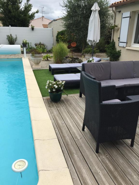une terrasse avec une piscine, des chaises et un parasol dans l'établissement maison avec piscine, à Saintes