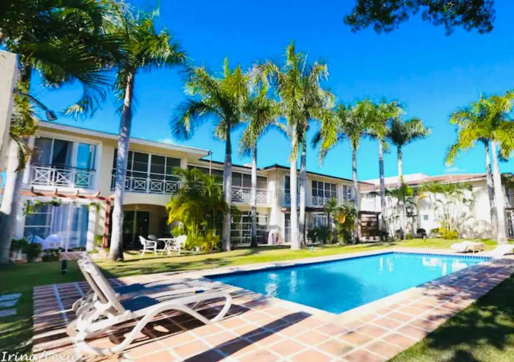 a villa with a swimming pool and palm trees at GLOBALSTAY Cocotal Condo in Punta Cana in Punta Cana