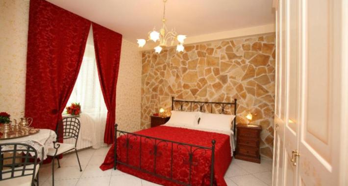 una camera con un letto rosso e una parete in pietra di Il Casale di Rodolfo a Termoli