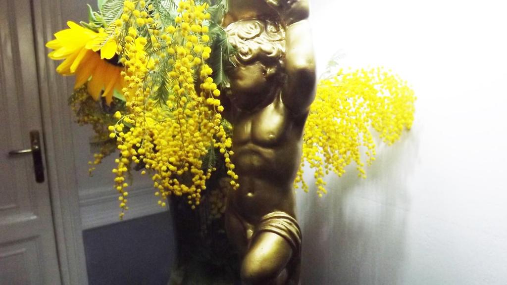 una estatua de una diosa con flores amarillas en una pared en Candia41, en Roma