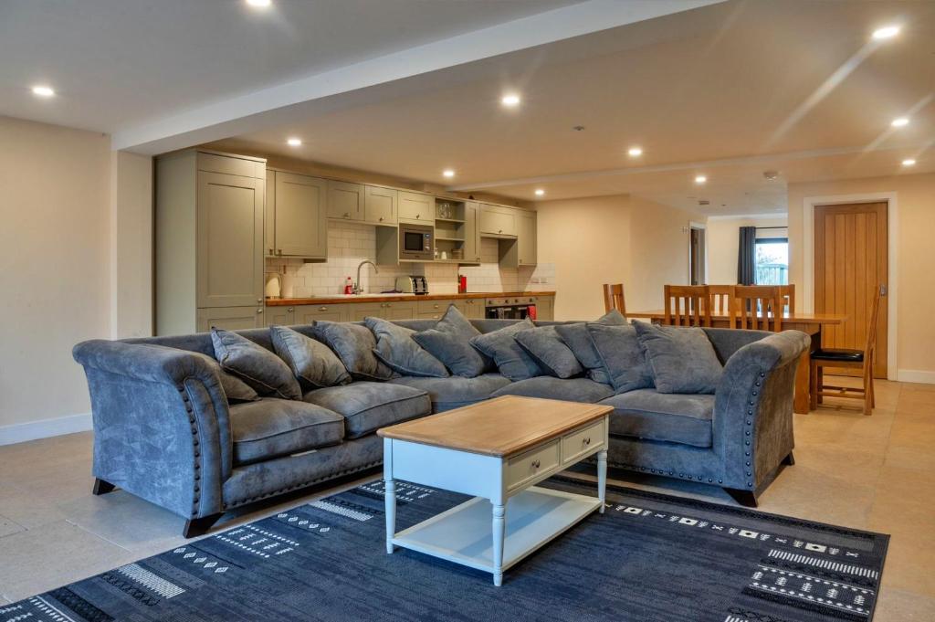a living room with a blue couch and a kitchen at Little Rissington - Barn Eight in Little Rissington
