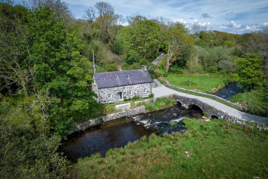 an aerial view of a stone house next to a river at Otter Cottage in Pwllheli