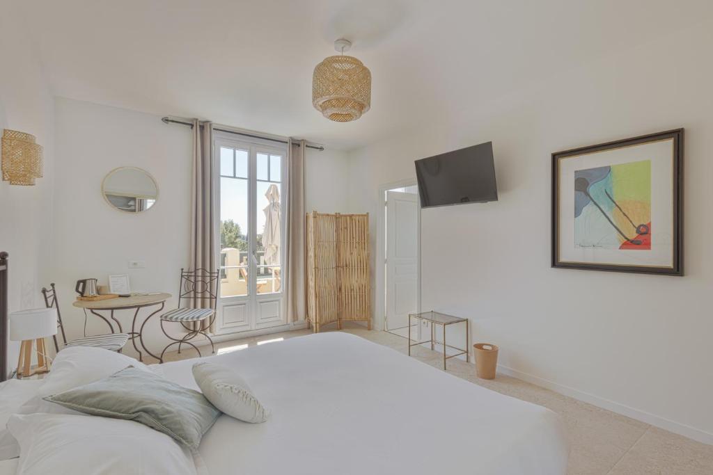 a white bedroom with a large bed and a table at La Garoupe-Gardiole in Antibes