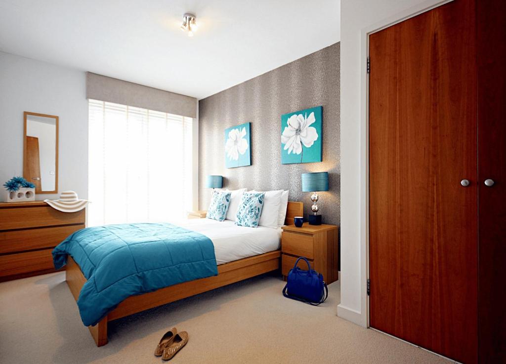 a bedroom with a bed with a blue blanket and a window at Reading Spacious Two Bedroom Apartment in Reading
