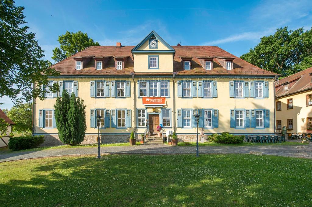 ein großes gelbes Gebäude mit rotem Dach in der Unterkunft Hotel Zum Herrenhaus in Behringen