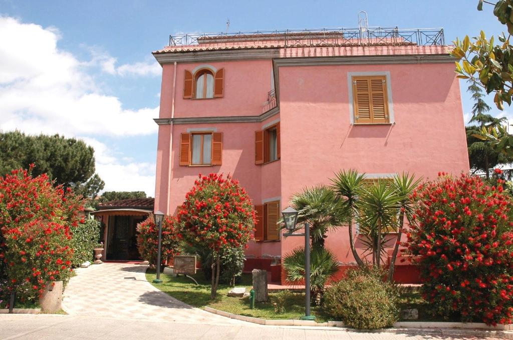 różowy budynek z czerwonymi kwiatami przed nim w obiekcie Hotel Arco Di Travertino w Rzymie