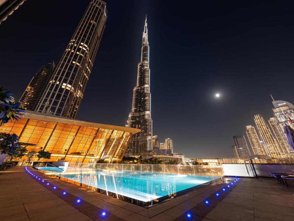 Hotel Grande Signature - 1BDR - Infinity Pool Burj Khalifa View, Dubai Mall, Opera House, a pool in the middle of a city at night at Grande Signature - 1BDR - Infinity Pool Burj Khalifa View, Dubai Mall, Opera House in Dubai