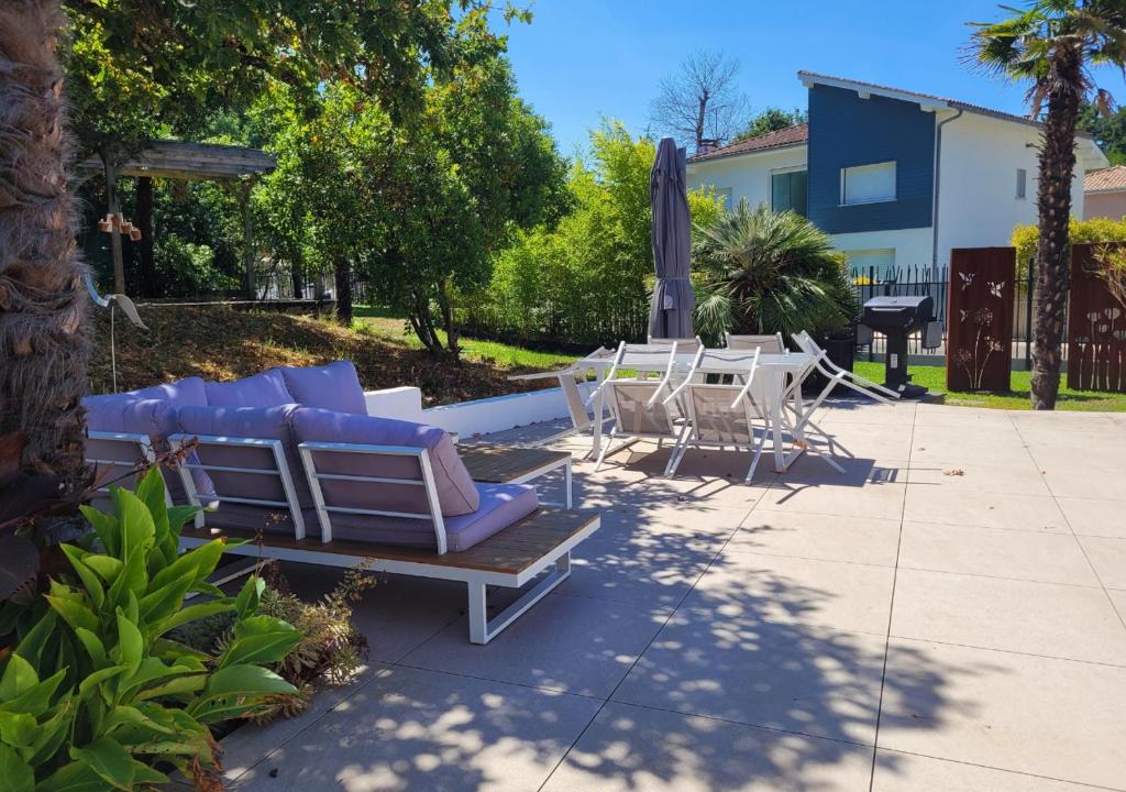 a group of lounge chairs and an umbrella on a patio at BRUYERES - Capbreton, belle villa spacieuse entre ville et plages au calme in Capbreton