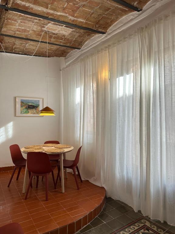 a dining room with a table and chairs and curtains at Apartamento El Tozal in Teruel