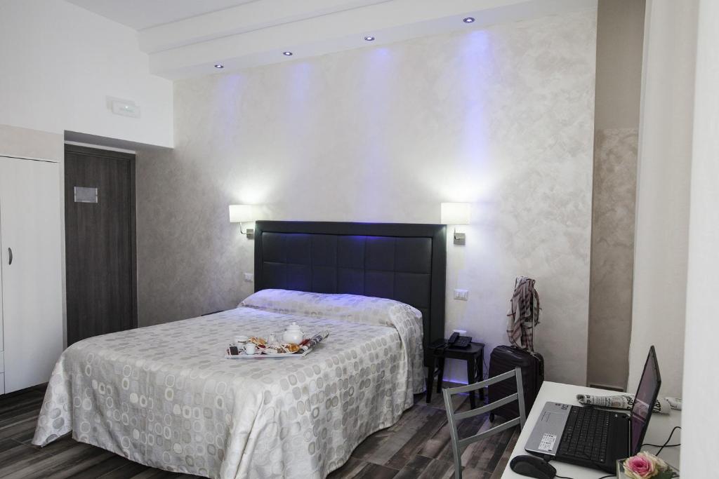 a bedroom with a bed and a desk with a laptop at Napoli Garibaldi Square in Naples