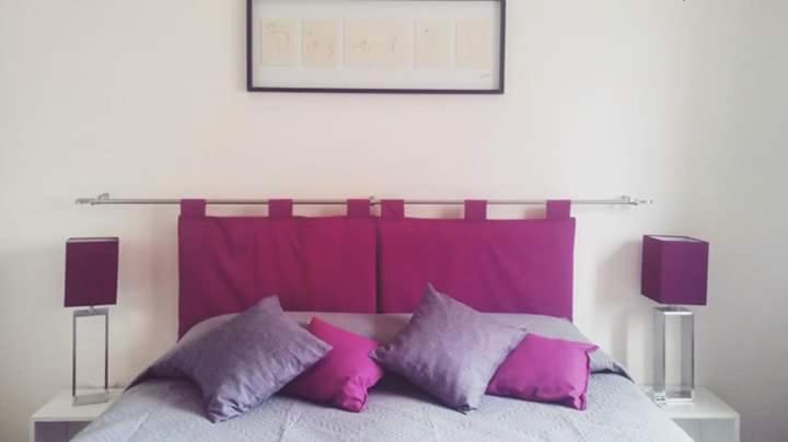レッジョ・ディ・カラブリアにあるB&B La Peoniaのピンクと紫の枕が付いたベッド
