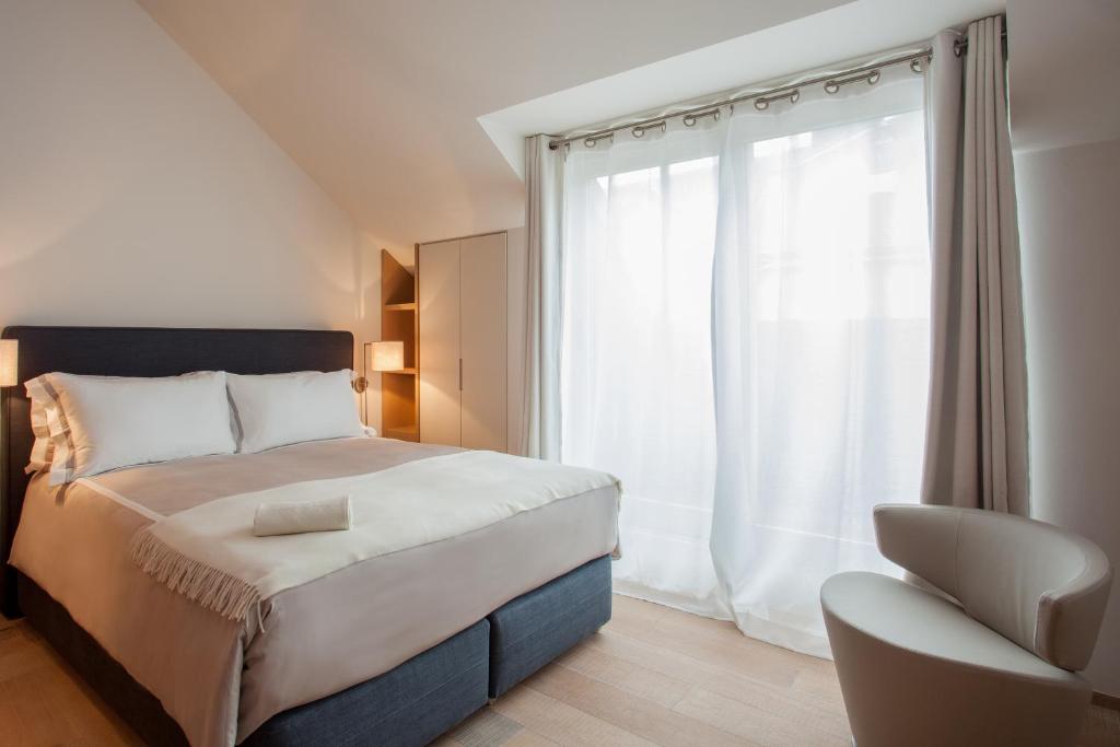 a bedroom with a bed and a chair and a window at Guillaume Suites in Luxembourg