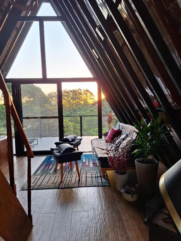 a living room with a couch and a large window at Chalé Guiados Pelo Alto in São Pedro de Alcântara