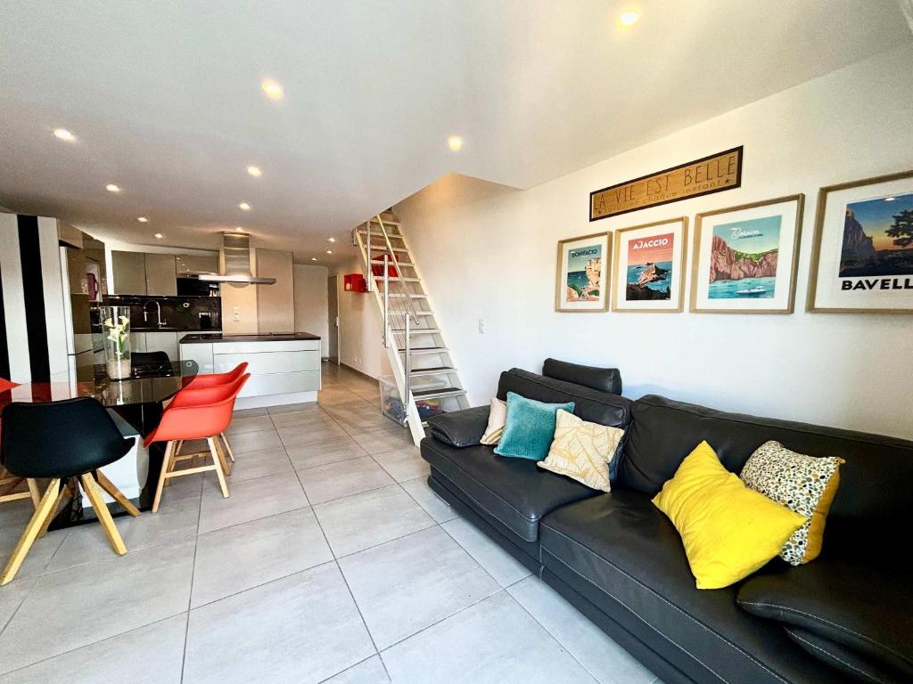 un salon avec un canapé noir et une cuisine dans l'établissement Casamea - Plage 20m, Vue Mer, Famille, à Porticcio