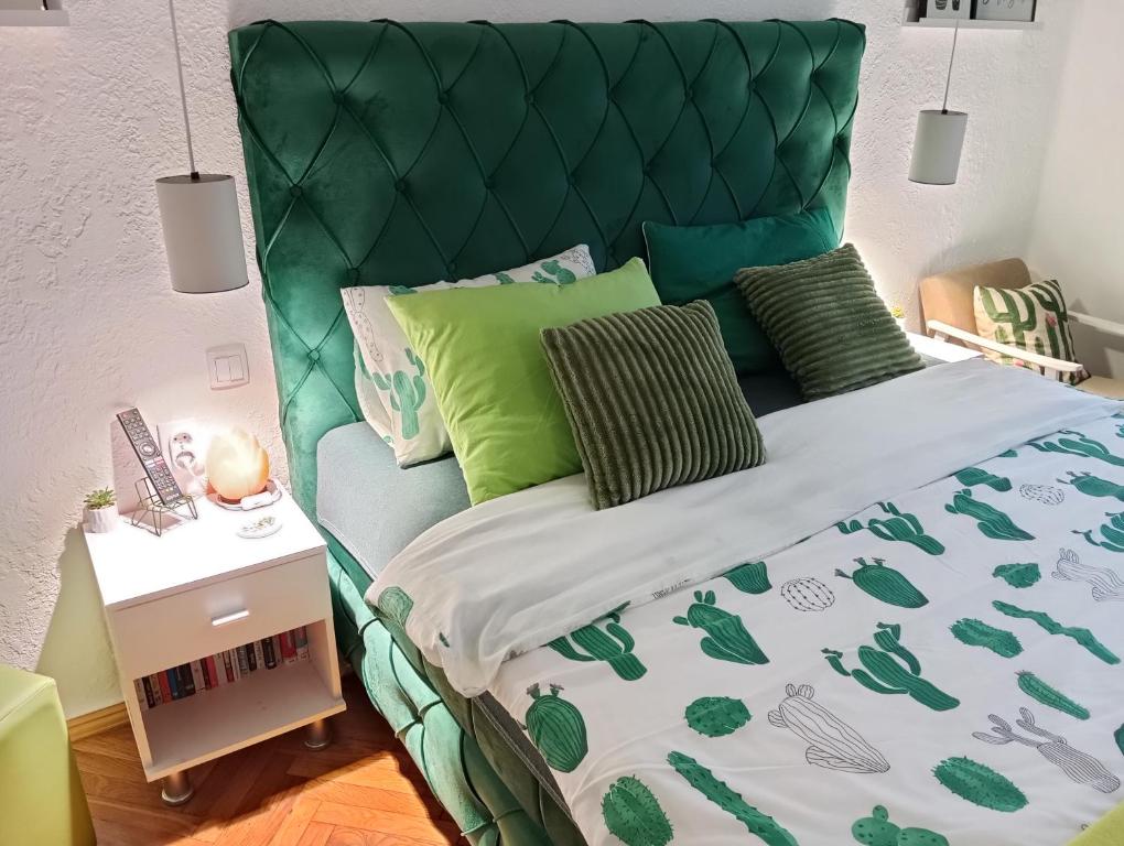 a bed with a green headboard and green pillows at Green Cactus Rooms - unique and cozy house in Senta