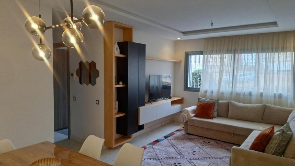 a living room with a couch and a television at Bel appartement familial résidence sécurisée in Casablanca
