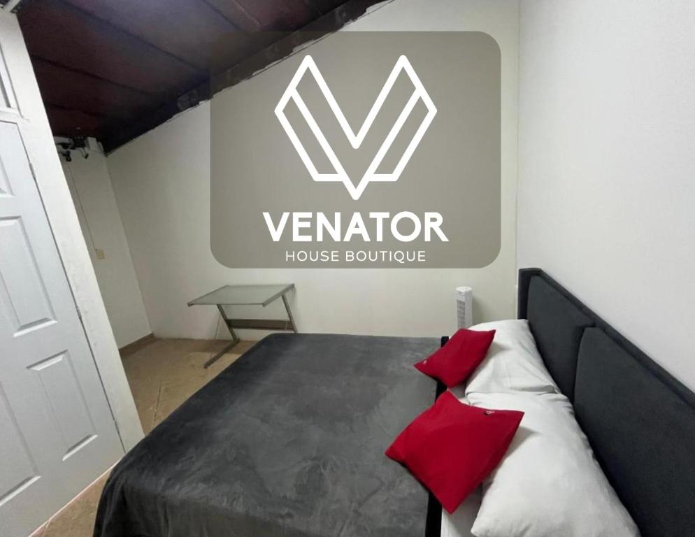 a bedroom with a bed with red pillows in front of a sign at Venator House Habitación sencilla #17 in Miravalle