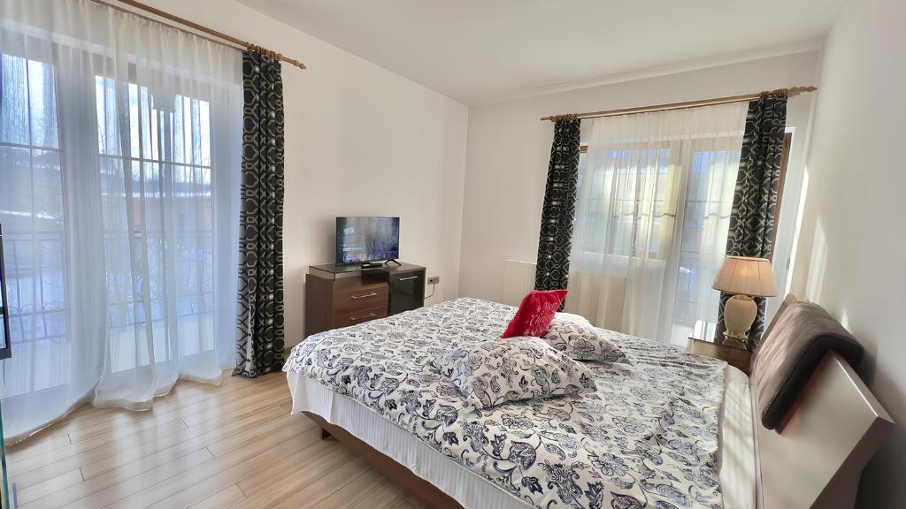 a bedroom with a bed and a tv and windows at Apartamente Simona Brasov in Braşov