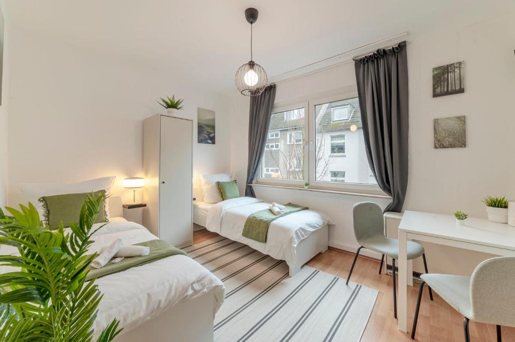 ein Schlafzimmer mit zwei Betten und einem Schreibtisch und einem Tisch in der Unterkunft Eco Retreat Spacestays - Smart TV - WIFI in Essen