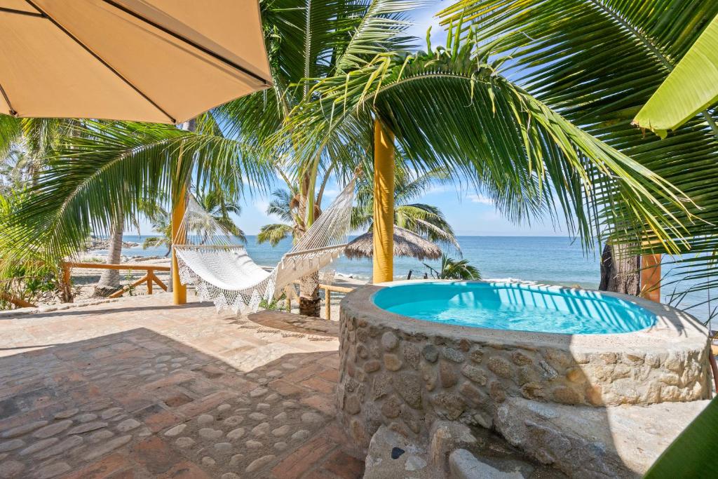 een hot tub op het strand met een palmboom bij Panchos Paradise Cabaña Parota in Puerto Vallarta