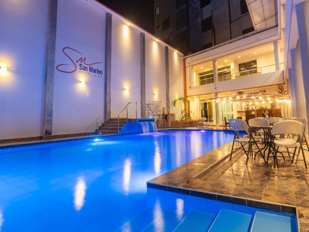 a swimming pool with chairs and a table in a building at Hotel San Marino Tarapoto in Tarapoto