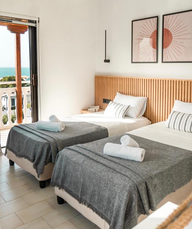 a hotel room with two beds and a balcony at Sea View Studio at Xenios Avlais in Zakynthos Town