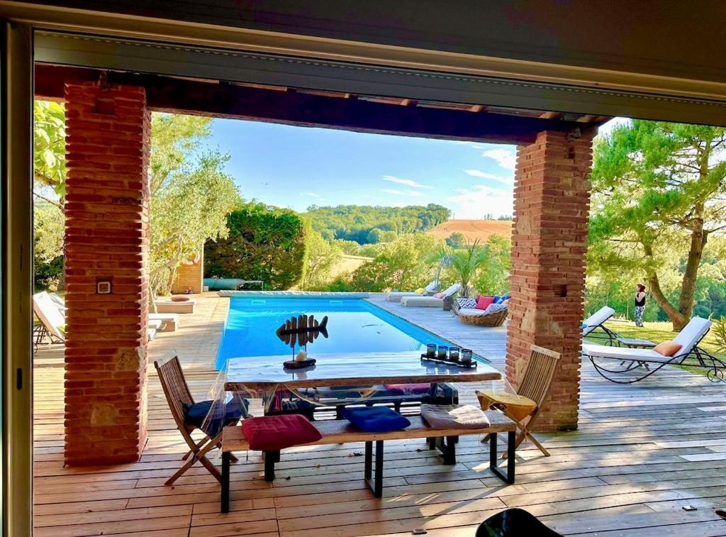 un patio avec une table et des chaises et une piscine dans l'établissement Ferme Le Bacou, à Caraman