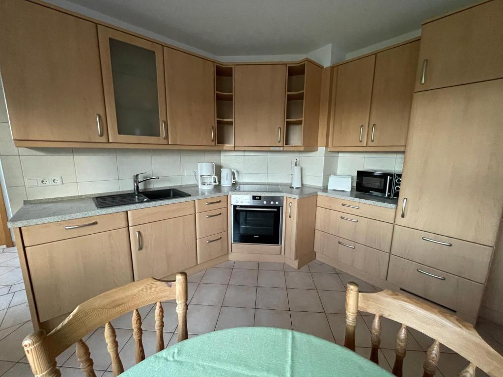 a kitchen with wooden cabinets and a table and chairs at Sommertraum im Hasetal, Becksvoort-Noll in Löningen