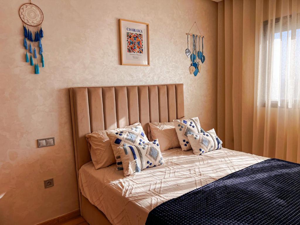 a bedroom with a bed with blue and white pillows at Appartement Vue Mer & Coucher de Soleil in Aïn Harrouda