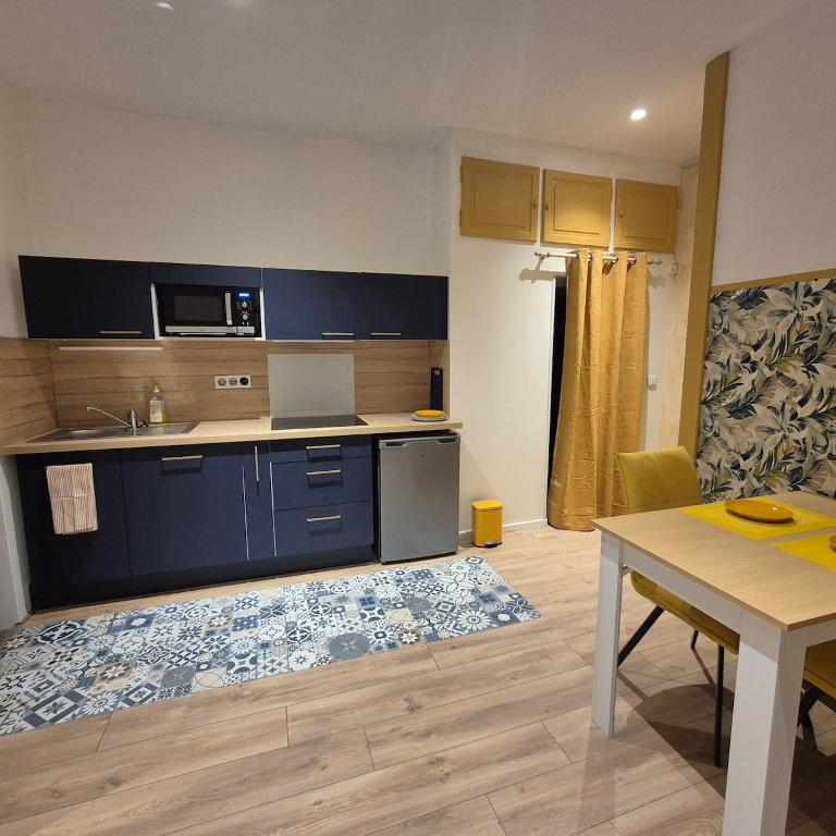 une cuisine avec des armoires bleues et une table ainsi qu'une salle à manger dans l'établissement superbe studio proche centre, à Chambéry