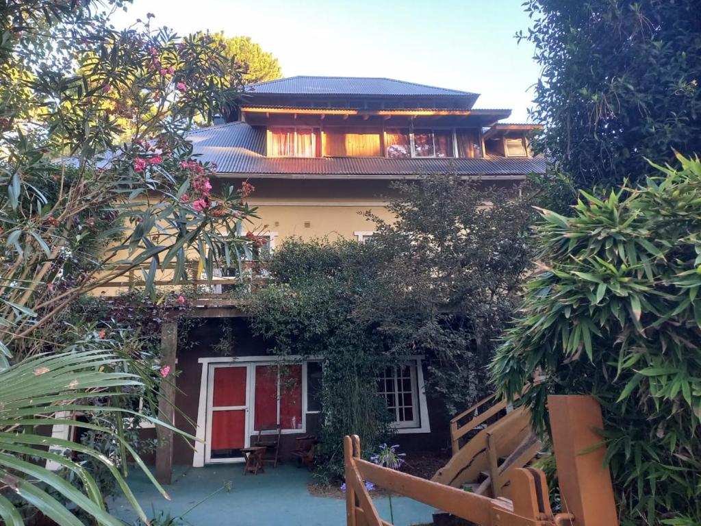 Una casa con una puerta roja y algunas plantas. en Puerto Principe, en Pinamar