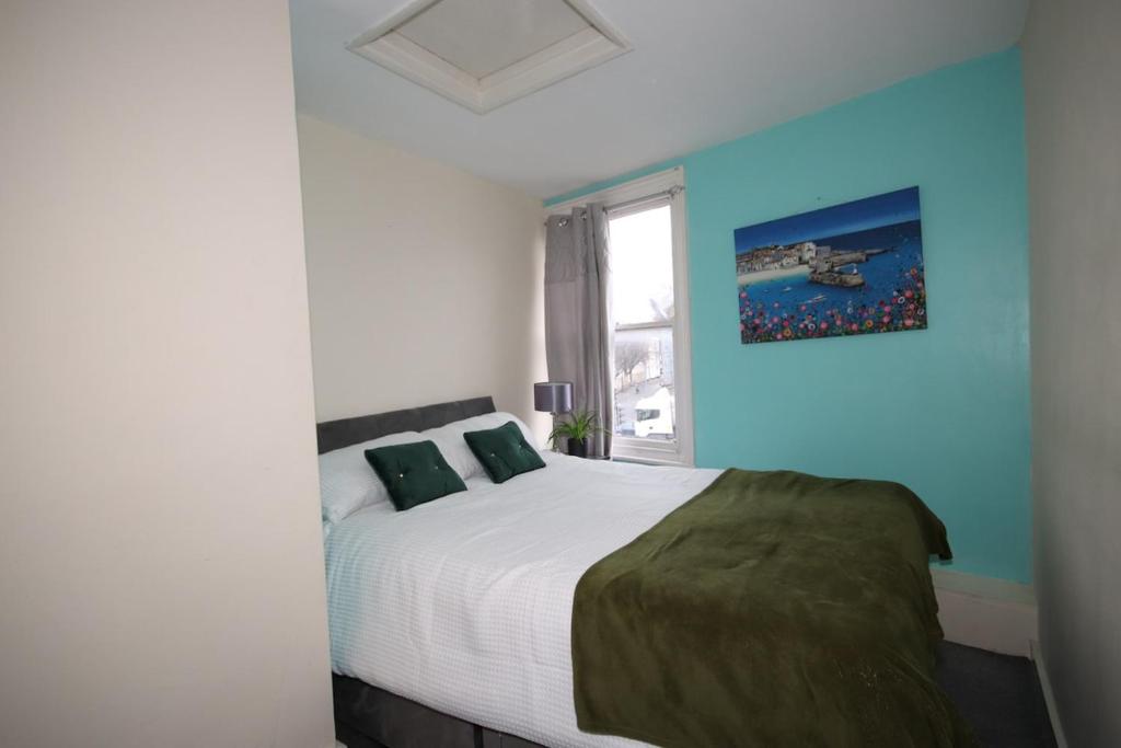 a bedroom with a bed and a blue wall at City heights Central location in Canterbury