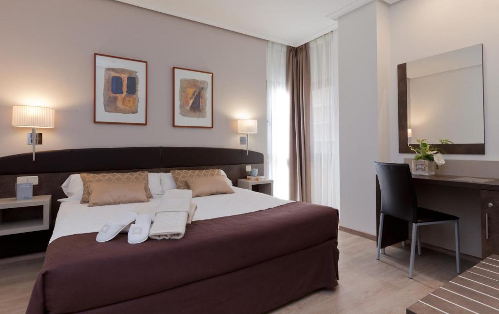 a bedroom with a large bed with a desk and a chair at Hotel Villamadrid in Madrid