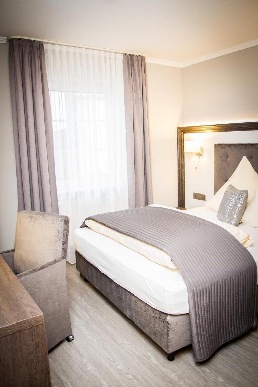 een slaapkamer met een bed, een stoel en een raam bij Haus Anna an der Stadtmauer in Hanau am Main