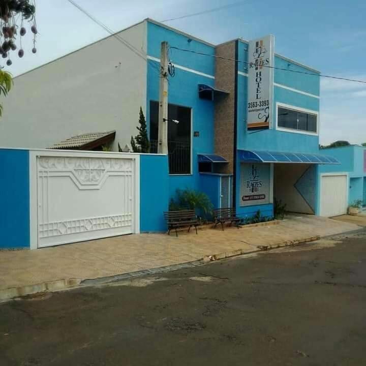 a blue building with a bench in front of it at Raízes Hotel in Cajobi