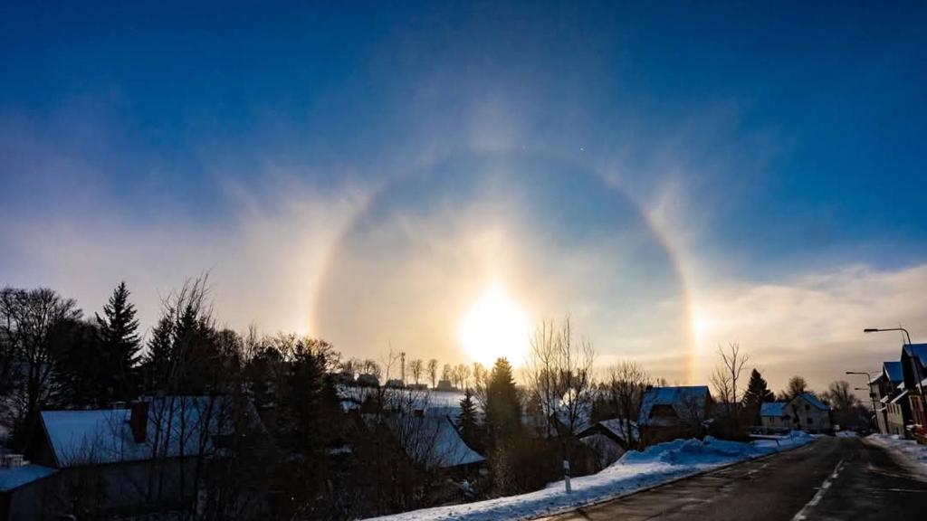 a rainbow in the sky over a snowy street at Pension MAX in Pernink