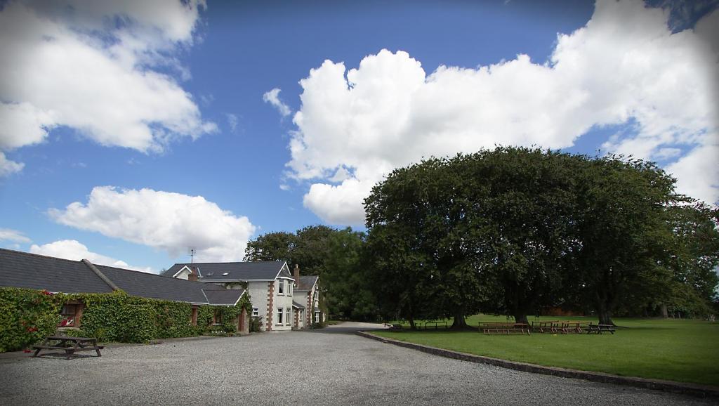 une maison avec un arbre et des bancs dans un parc dans l'établissement Coolanowle Self Catering Holiday Accommodation, à Carlow