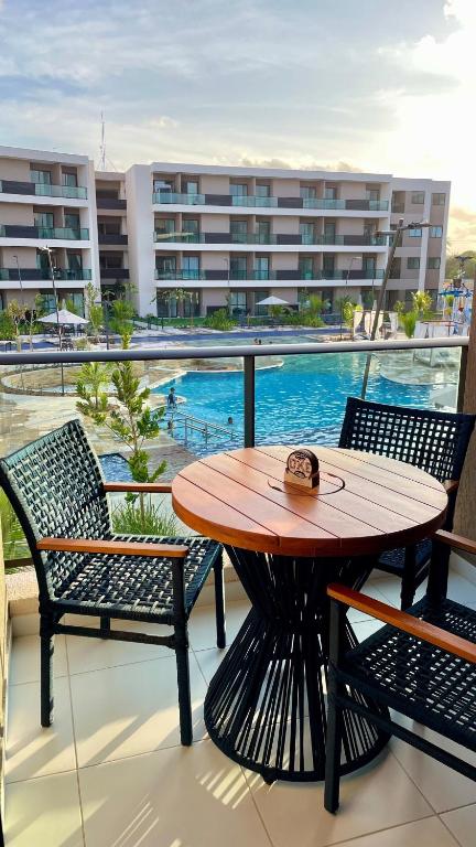 a table and chairs on a balcony with a pool at Malia Muro Alto - Porto de Galinhas - Flat para 5 pessoas vista piscinas in Ipojuca
