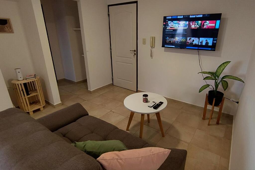 ein Wohnzimmer mit einer Couch, einem Tisch und einem Fernseher in der Unterkunft Departamento Moderno - Punto Alto in Villa María