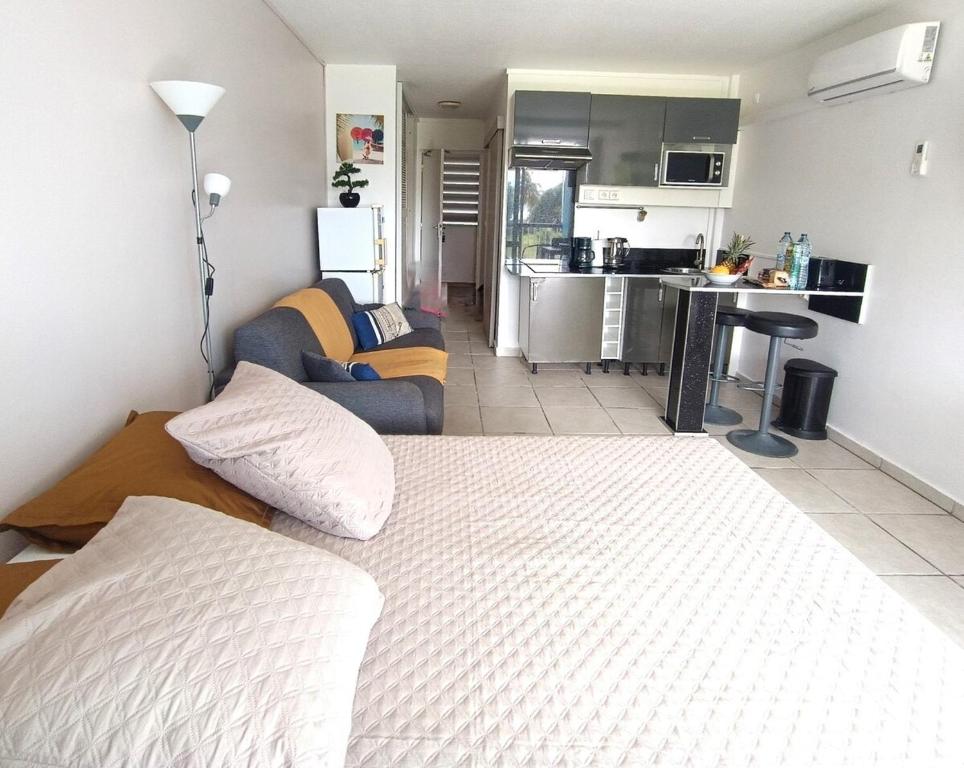 Un dormitorio con una cama blanca y una cocina. en Studio vue Mer Gosier, Guadeloupe, en Le Gosier