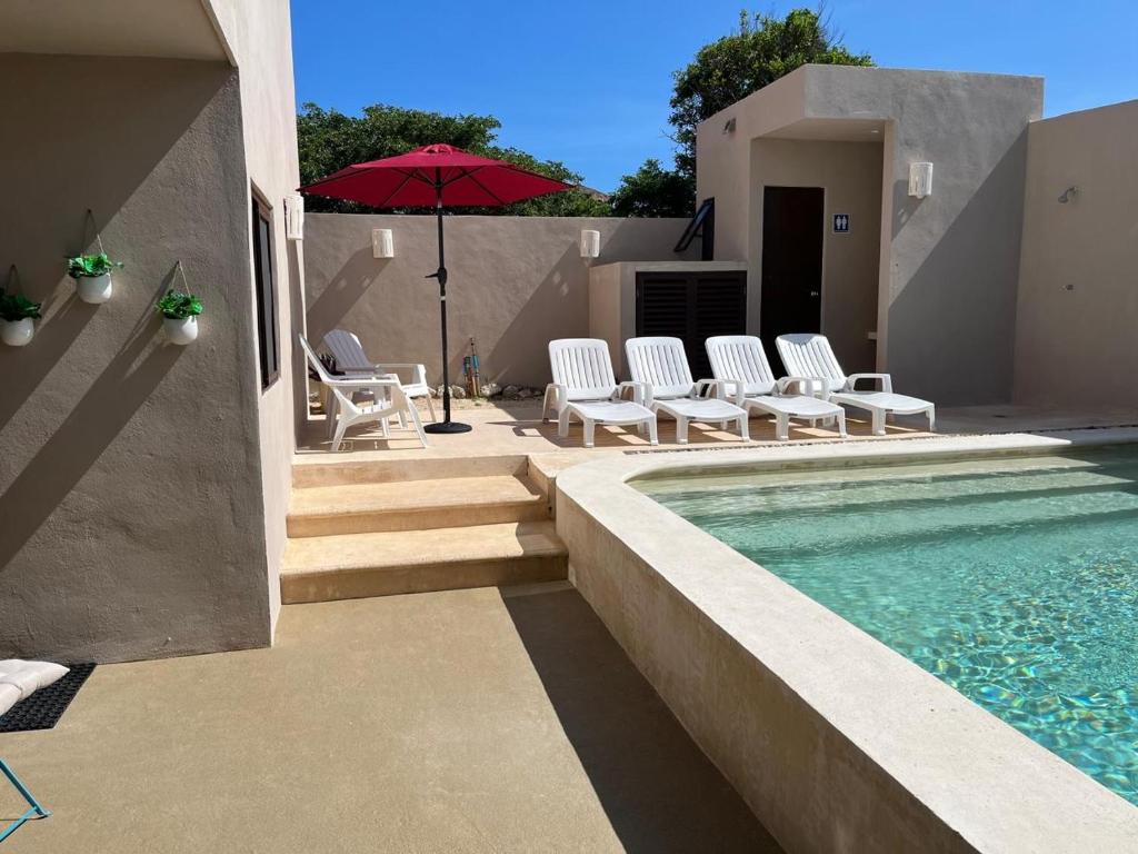 a pool with chairs and an umbrella next to a house at Mar y Chelo Luxury Aparments in Isla Mujeres