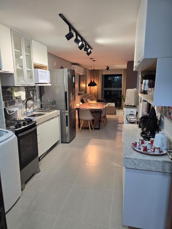a kitchen with white appliances and a table in it at Charme e requinte em Carneiros com 2 quartos in Tamandaré