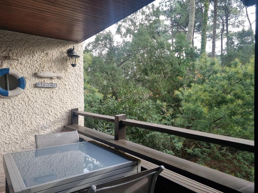 d'un balcon avec une table et une vue sur les arbres. dans l'établissement Spacieux T3 à Seignosse au bord de l'océan avec balcon - FR-1-239-1095, à Seignosse