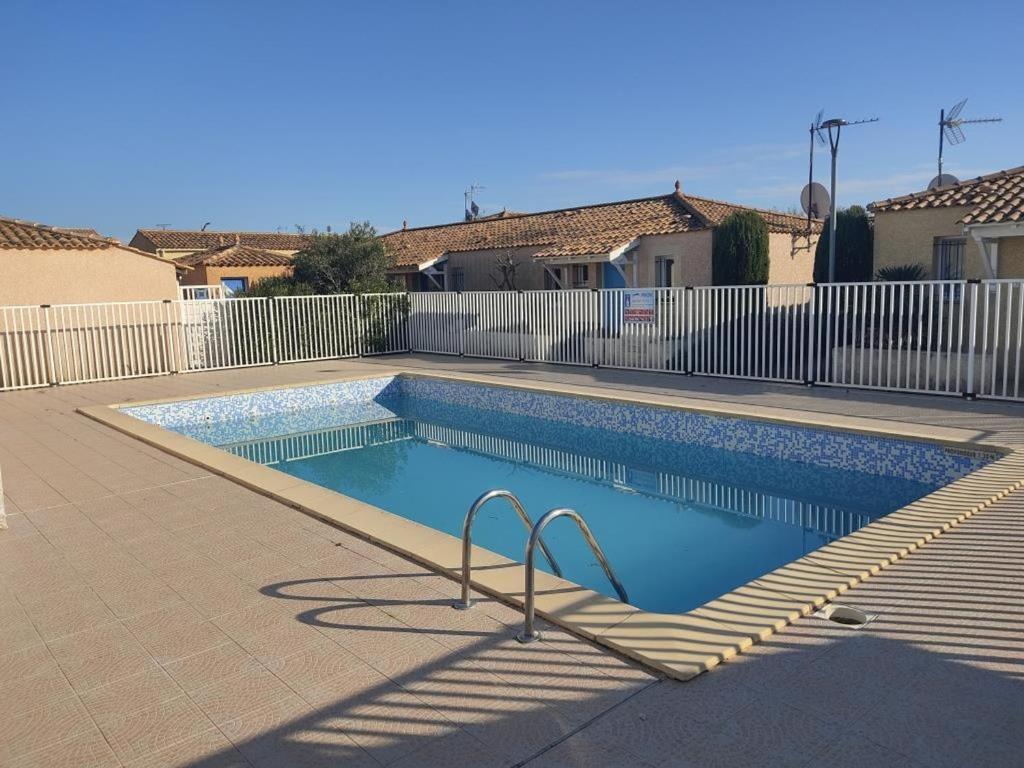 une piscine en face d'une clôture blanche dans l'établissement Villa 4/6 pers climatisée avec piscine, WiFi & parking proche plage - FR-1-796-85, à Gruissan