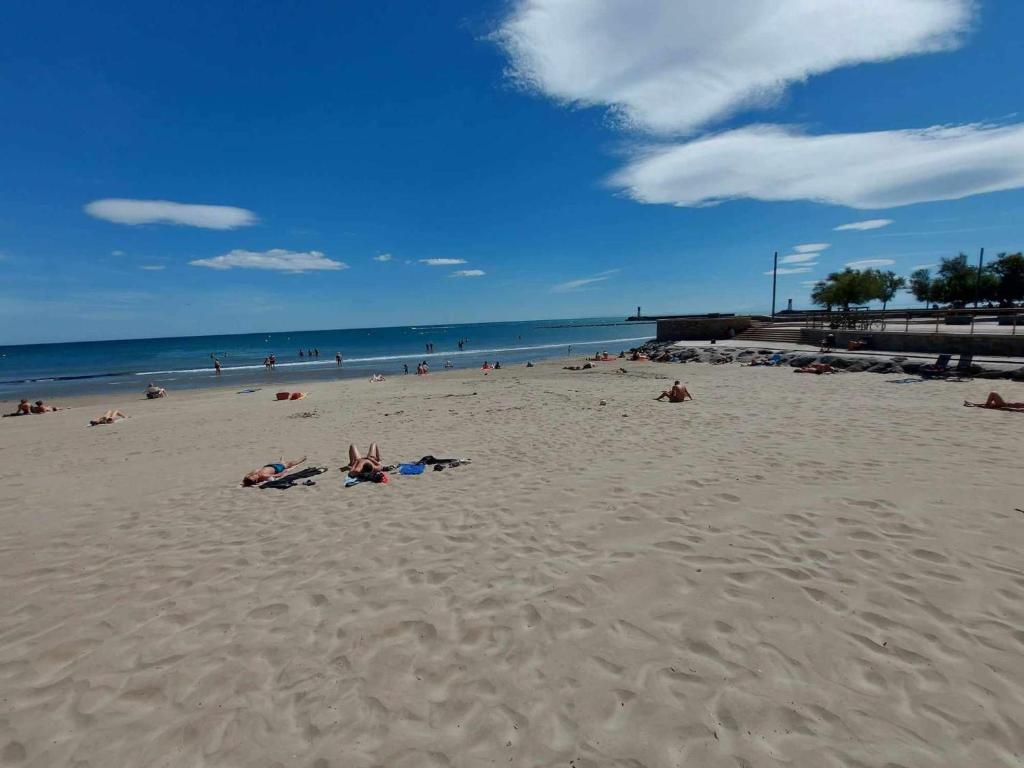 un groupe de personnes allongées sur une plage dans l'établissement Appartement 2 pièces climatisé en front de mer pour 4 personnes - FR-1-423-313, au Grau-dʼAgde