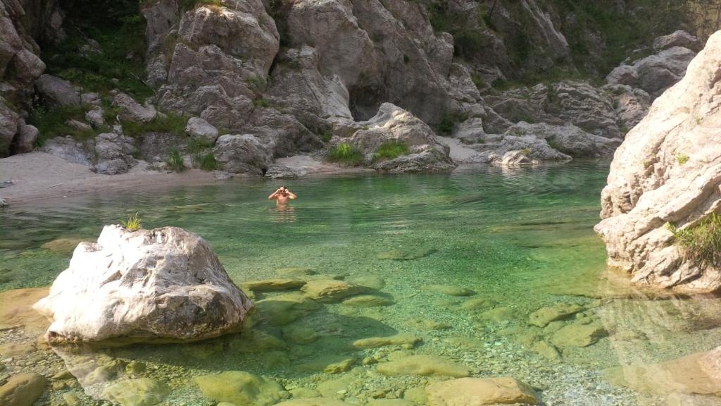 a person swimming in a river with a rock in the water at Agriturismo Borgo Titol in Tramonti di Sopra