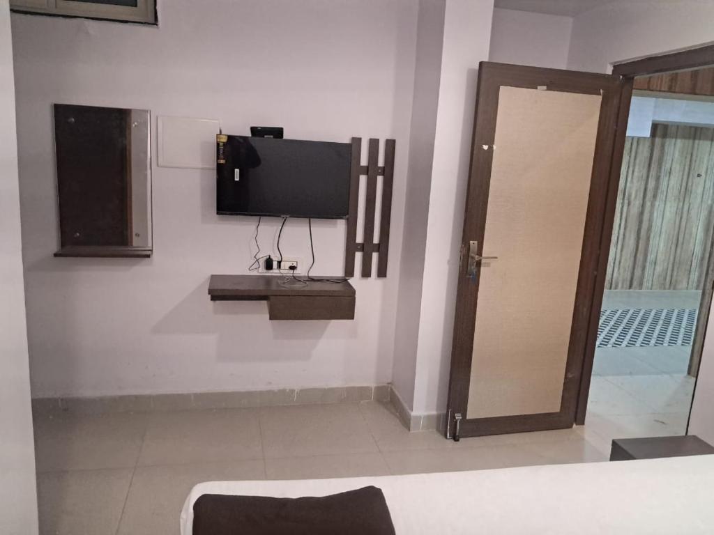 a room with a tv on the wall and a door at Aahvaanam in Kurnool